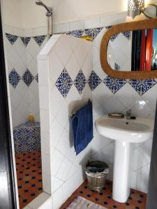 uma casa de banho com paredes em azulejos azuis e brancos e um lavatório. em Dar Nadia em El Jadida