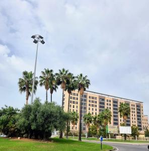 un gran edificio con palmeras y luz de la calle en Alazán Jerez II-Parking gratis-wifi-Netflix, en Jerez de la Frontera
