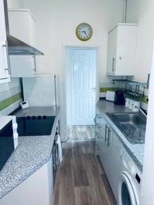 a kitchen with a sink and a clock on the door at Comfortable town house in Coventry City Centre in Coventry