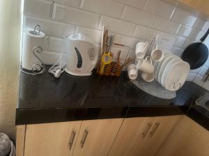 a counter top with cups and utensils on it at Ruby Modern Homes Studio-Imara Daima,Behind Imaara Mall-JKIA-Horizon in Nairobi
