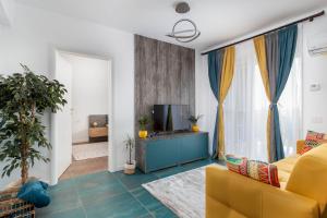 uma sala de estar com um sofá amarelo e uma televisão em Talida's apartment colorful and brightnes em Oradea