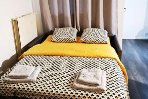 a bed with two pillows and a yellow and white mattress at Le Jules Val - Studio cosy en résidence + Parking + Wi-fi in Évry-les-Châteaux
