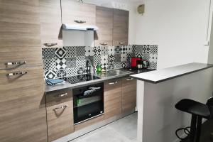 uma cozinha com armários de madeira e um forno com placa de fogão em Le Jules Val - Studio cosy en résidence + Parking + Wi-fi em Évry-les-Châteaux