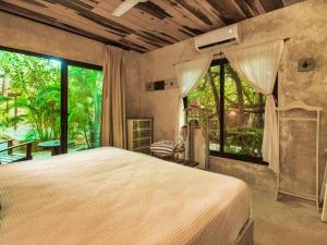 a bedroom with a large bed and large windows at Suites Tulum in Tulum