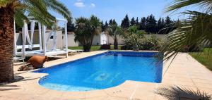 a blue swimming pool with a bench next to a house at Appartement Carpe diem in Orange