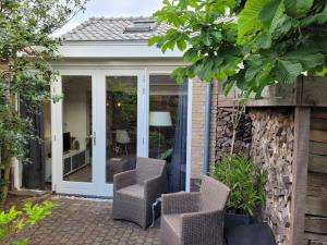 a conservatory with glass doors and chairs on a patio at Ferienhaus Noordwijk Zee & Strand in Noordwijk