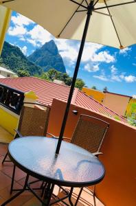 a table and chairs with an umbrella on a balcony at Apartment Soleil- Because Location really is everything! in Soufrière