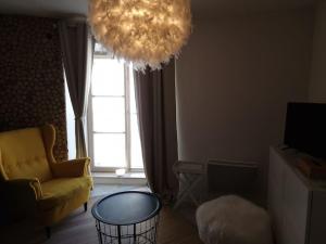 een woonkamer met een gele stoel en een kroonluchter bij Petit cocon quartier historique Chaumont in Chaumont