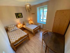 a room with two beds and a table and a window at La grande marmite du lac de Vouglans in Pont-de-Poitte