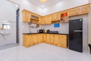 una cucina con armadi in legno e frigorifero nero di The Blue Haven Vung Tau a Vung Tau