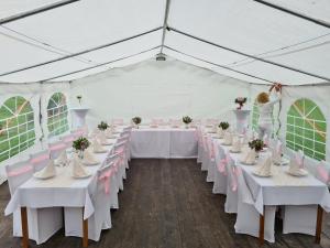 una carpa preparada para una boda con mesas blancas y sillas rosas en Chata u Petrenkov, en Horná Turecká