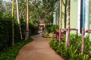 a walking path in front of a house with trees at Jinda Resort in Nai Yang Beach