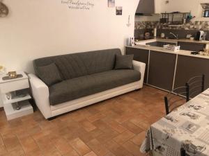 a couch in a living room with a kitchen at LA CASA DI ZOE in Campiglia Marittima