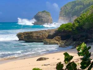 a beach with rocks and the ocean with waves at Caribbean Ashanti Lodge in Trois-Rivières
