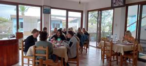 a group of people sitting at tables in a restaurant at Hotel Sula Sula in Puerto Villamil