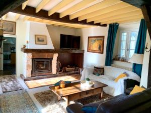 sala de estar con sofá y chimenea en La Ferme Familiale, en Faverolles