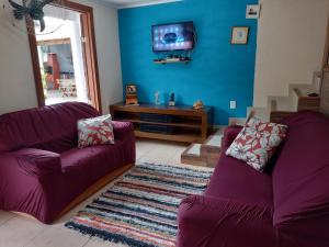 een woonkamer met twee paarse banken en een tv bij Casa com piscina em condomínio in Paraty