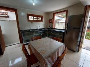 een keuken met een tafel, een wastafel en een koelkast bij Casa com piscina em condomínio in Paraty