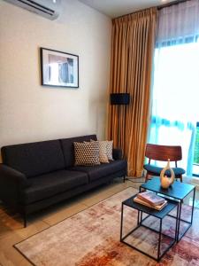een woonkamer met een zwarte bank en een tafel bij Staycationbyrieymona - 3BR Condo, CLIO 2, Putrajaya in Putrajaya