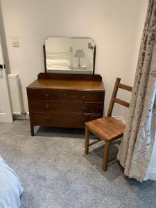 a bedroom with a dresser and a chair and a mirror at The Victorian Apartment in Dundee