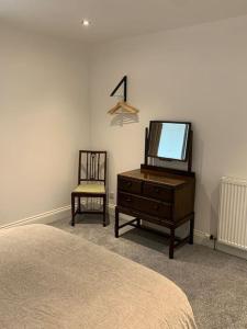a bedroom with a dresser and a tv and a chair at The Victorian Apartment in Dundee