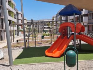 a playground with an orange slide in front of a building at Chinchorro Arica in Arica