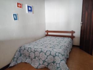 um quarto com uma cama com uma colcha em Casa pé na areia - 4m da praia! em São Pedro da Aldeia