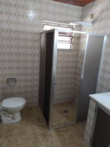 a bathroom with a toilet and a shower stall at Casa pé na areia - 4m da praia! in São Pedro da Aldeia +10 photos