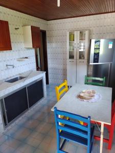 uma cozinha com uma mesa e cadeiras e um frigorífico em Casa pé na areia - 4m da praia! em São Pedro da Aldeia