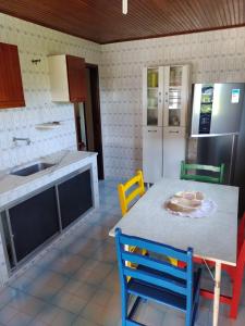 a kitchen with a table and chairs and a refrigerator at Casa pé na areia - 4m da praia! in São Pedro da Aldeia