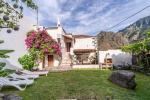 a white house with a yard with chairs and flowers at Casa Buganvilla in Hermigua
