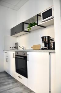 eine Küche mit weißen Schränken und einem schwarzen Backofen in der Unterkunft Apartman Favorita in Wien