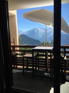 a table and chairs on a balcony with an umbrella at Vue exceptionnelle ALPE D HUEZ in LʼHuez