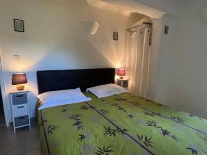 ein Schlafzimmer mit einem Bett mit einer grünen Decke und 2 Lampen in der Unterkunft Chambres et tables d'hôtes Zélia & Jacques BERQUEZ in Pianottoli-Caldarello