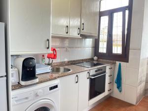 una pequeña cocina con armarios blancos y fregadero en Apartamento a pie de playa en Mogro en Mogro