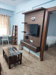 Kamadhenu Residency Homestay Hotel Coorg Madikeri في ماديكيري: غرفة معيشة مع تلفزيون في جدار من الطوب