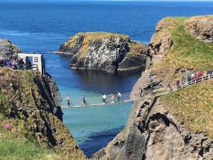 people crossing a suspension bridge over the ocean on a cliff at Cosy Loft Apartment in Ballycastle