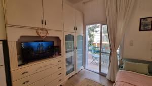 a living room with a television and a balcony at Lovely studio with balcony in Rechovot