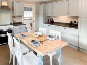 a kitchen with a wooden table and white cabinets at Nether Clashnoir in Auchnarrow