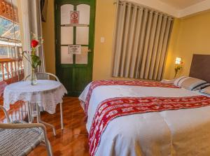 una camera da letto con un letto, un tavolo e una finestra di Hotel Willcamayu a Písac