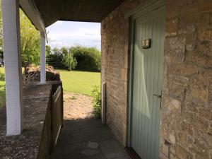 a doorway to a brick house with a green door at Cotswold Merrymouth Inn in Bourton on the Water