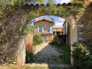 an archway leading to an old stone house with flowers at L'Arbre d'Alice in Ongles