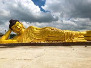 a large golden statue of a woman laying down at Nilam Guest House in Bodh Gaya