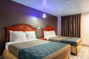 2 camas en una habitación de hotel con paredes púrpuras en Summit Inn - Houston Medical Center - NRG Park, en Houston
