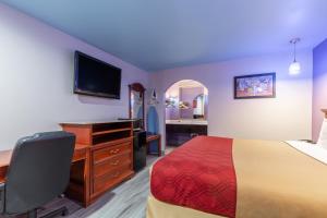 Habitación de hotel con cama, escritorio y TV. en Summit Inn - Houston Medical Center - NRG Park, en Houston