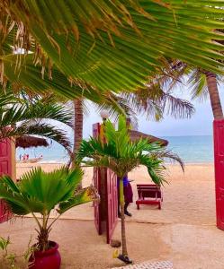 a sandy beach with palm trees and the ocean at Maison Couleur Passion in Nianing
