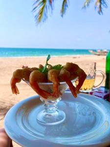 a glass dish with shrimp on a plate on the beach at Maison Couleur Passion in Nianing