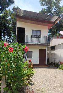 Casa con balcón y flores rojas en Cabinas Playa Agujas, en Quebrada Ganado