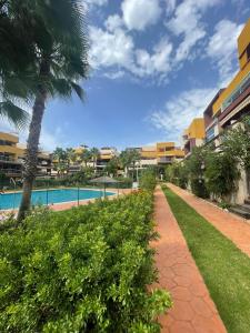 a resort with a swimming pool and a palm tree at Casa Palmera - El Bosque - Playa Flamenca in Playa Flamenca