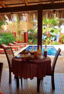 una mesa con bebidas en ella con sillas y una piscina en Maison Couleur Passion, en Nianing